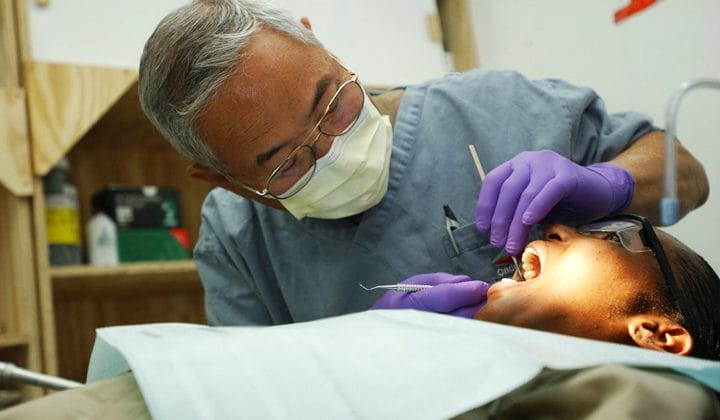 dentist in purple gloves performing treatment on patient