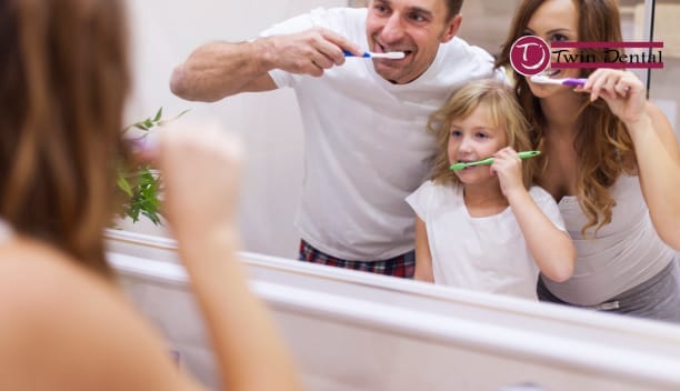 family brushing teeth together in front of mirror