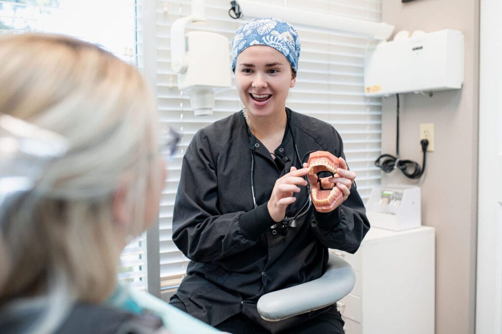 Hygienist explaining teeth whitening using a dental model.